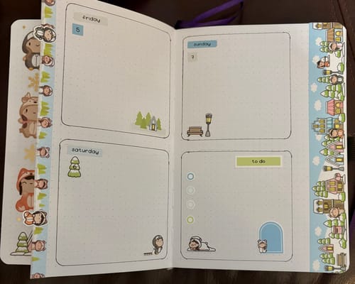 Customer's open journal showing a weekly layout for Friday-Sunday decorated with stickers from the Winter Onesie Town Journal Pack.