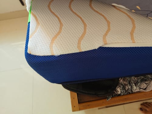Close-up of a customer's Flo Mattress Ortho, showing the white patterned top cover and blue mesh side panel.