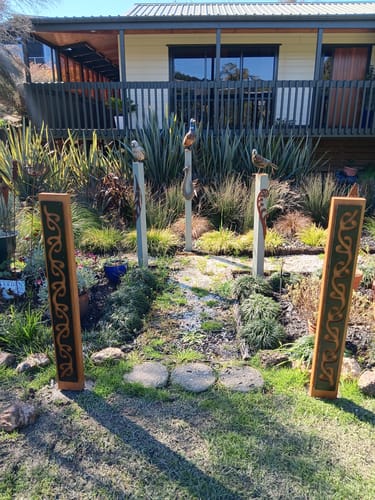Customer photo review of Black metal Long Koru pattern on Rustic Oak Post-Garden Art