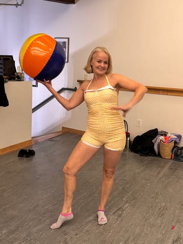 Reviewer posing indoors in the yellow Gingham 1950s Halter Swimsuit while holding a colorful beach ball.