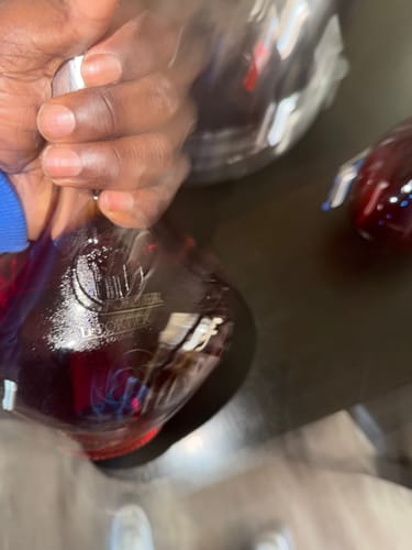 Close-up, blurry view of a customer holding the Le Portier Shay VSOP Cognac bottle.