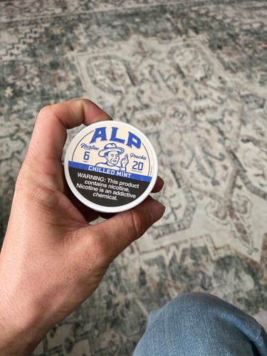 Customer's hand holding a round, white can of Chilled Mint Nicotine Pouches.