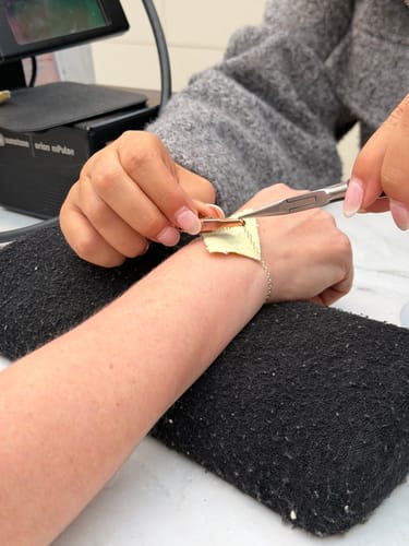 Close-up of a customer getting a delicate Sparked by FinerRings chain bracelet fitted onto their wrist.