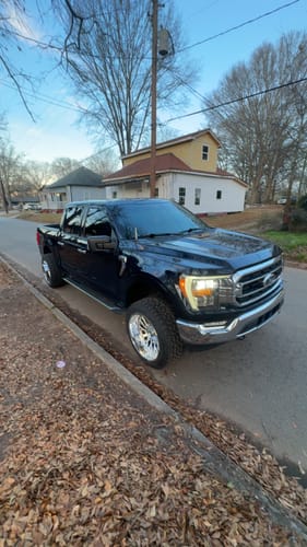 Customer's dark blue F-150 parked on a street showing its lifted stance from the 3" Front Leveling Lift Kit.