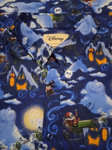 Close-up of a customer's blue "Here Comes Sandy Claws" shirt, showing the collar and Jack Skellington pattern.