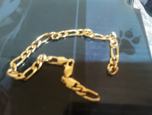 Cliente muestra la Pulsera Fígaro Oro rota sobre una superficie oscura.
