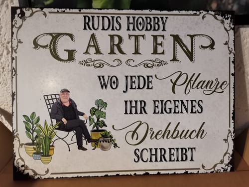 Rezensent zeigt das personalisierte Gartenschild mit einer Foto-Illustration und dem Text „Rudis Hobby Garten“.