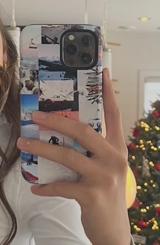 Customer's hand holding a custom iPhone 12 Pro Max case featuring a photo collage of skiing and winter scenes.