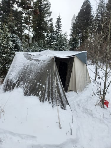 Reviewer's image of a tent in a snowy, wooded area, illustrating the cold conditions mentioned for the Men's Alpaca Socks.