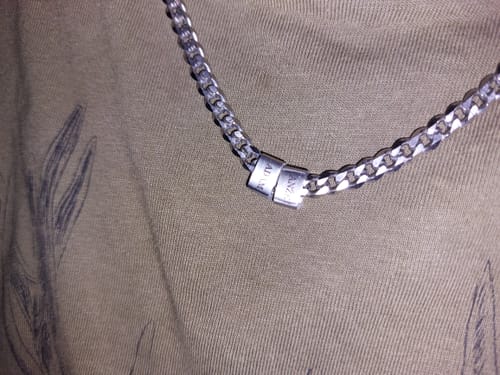 Close-up of a reviewer's stainless steel Legacy Necklace, showing two personalized beads on the chain against a fabric surface.