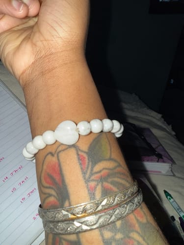 Reviewer wearing a white beaded crystal bracelet with a central heart-shaped stone on their wrist.