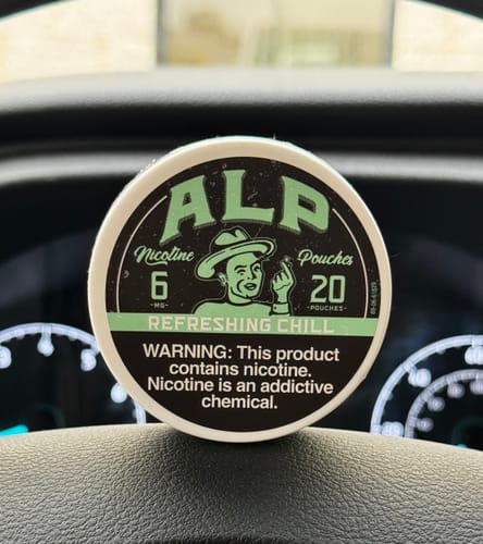 Customer's can of ALP Refreshing Chill Nicotine Pouches resting on a car dashboard.