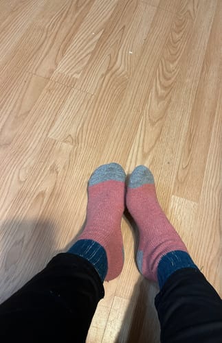 Customer wearing the thick wool socks, featuring a pink, grey, and blue color-block design.