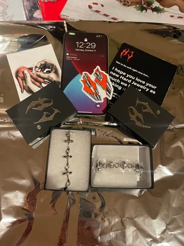 Customer displays their new DYT Bracelet with cross links in its open box next to a second bracelet.