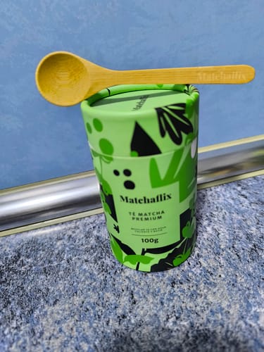 Un cliente muestra el envase verde del Té Matcha Premium con una cuchara de madera encima.