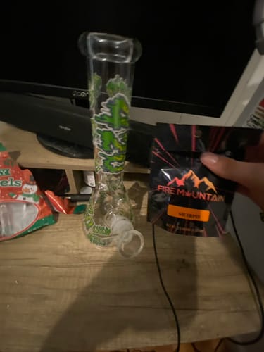 Customer's 420 Clouds beaker glass bong with green decals sitting on a wooden table.