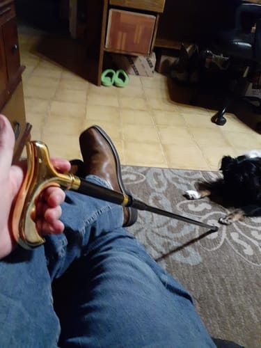Customer holding the black and gold sword cane with the blade partially extended across their lap.