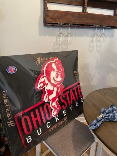 Customer's Ohio State 'Brutus' 3D metal artwork, still in its packaging, propped up on a chair.