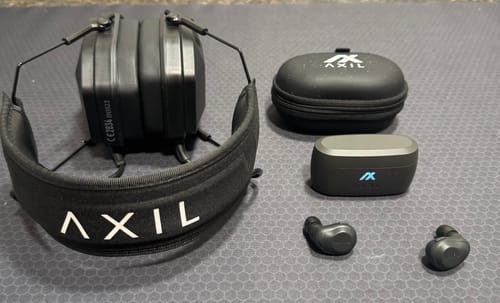 Reviewer's photo showing their black MX PRO earmuffs next to a pair of in-ear buds and their cases for comparison.