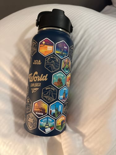 Customer's dark blue World Explorer Bottle decorated with colorful stickers of world destinations.