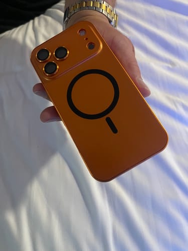 Customer holding the back of their orange MagCase Metal case, showing the MagSafe symbol.