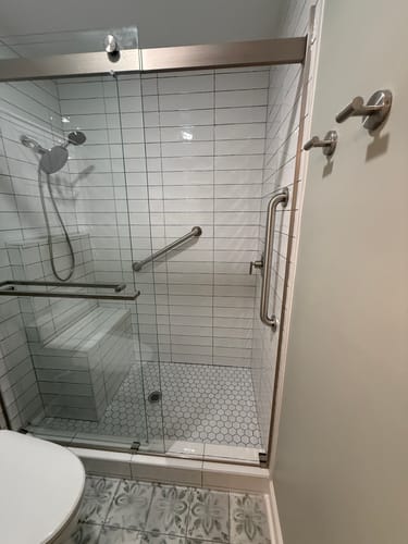 Customer's brushed nickel dual shower head set installed in a modern, white-tiled walk-in shower.