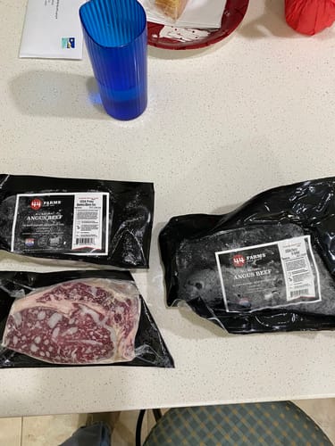 Customer's three frozen USDA Prime Boneless Ribeye Steaks in vacuum-sealed packages on a kitchen counter.
