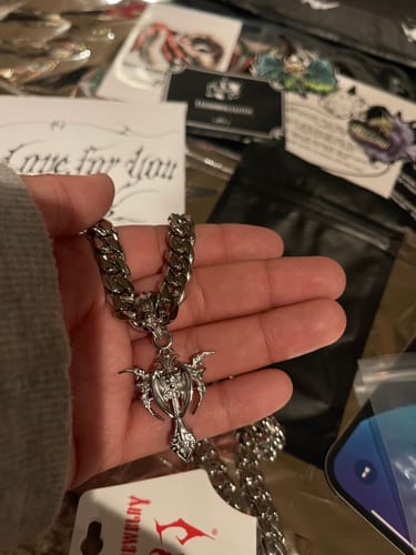 Customer holding the silver-colored Tribal Cross Pendant on a thick chain in their palm.