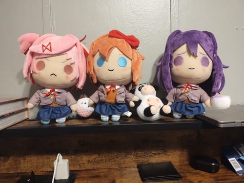 Customer's Yuri Collector's Plush with purple hair, sitting on a desk next to the Natsuki and Sayori plushies.