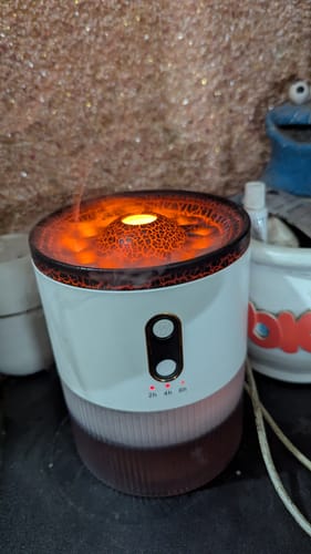 Customer's white Volcano Humidifier turned on, glowing with an orange light and releasing a wisp of mist.