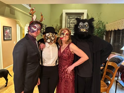 Reviewers in fun costumes and masks playing the Masquerade Ball Murder Mystery game at a holiday party.