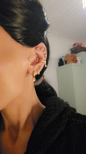 Customer's ear adorned with the Link Up Chain Cuff Gold, shown as part of a stylish gold ear stack.