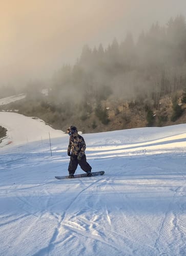 Customer snowboarding on a foggy mountain wearing the black baggy waterproof snow pants.