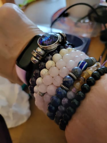 Close-up of a reviewer's wrist wearing a stack of colorful beaded crystal bracelets.