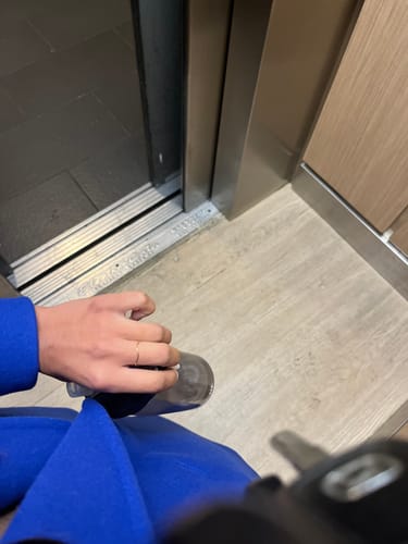 Customer wearing the thin Tina Gold Stack Ring on their finger, with their blue coat sleeve visible.