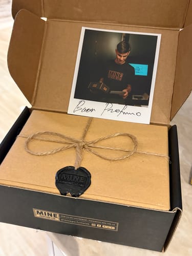 Cliente che apre la confezione del profumo OUD, mostrando l'elegante pacchetto con sigillo in ceralacca e una nota.