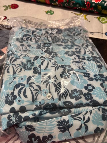 Customer's Disney 'Aloha Pal' shirt folded in its original clear packaging, showing the blue tropical pattern.