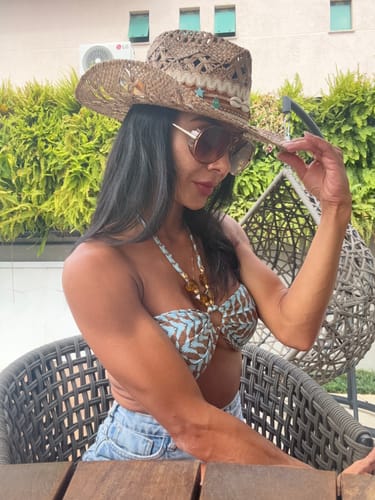 Cliente usando os óculos de sol Veneza oversized ao ar livre com um chapéu de palha.