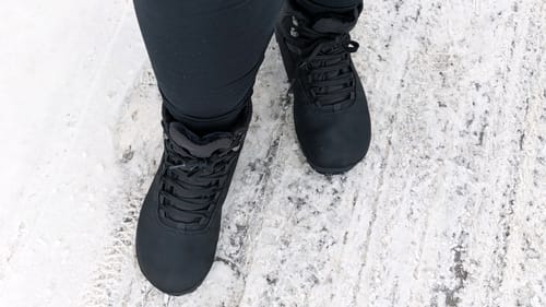 Asiakkaan mustat Vaistoa Uoma 3 Talvi -kengät jalassa lumisella ja jäisellä alustalla.