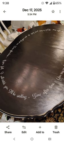 Close-up of a customer's white custom vinyl quote decal on a glossy black oval dining table.