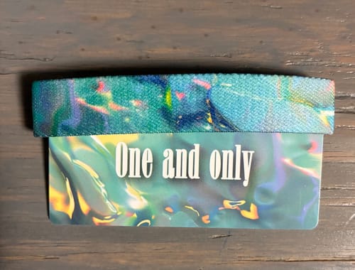 Customer's iridescent, teal One and only Bracelet displayed on its 'One and only' packaging card.