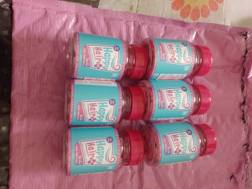 Cliente mostrando seis potes de suplemento Happy Hair em um envelope rosa de bolhas.