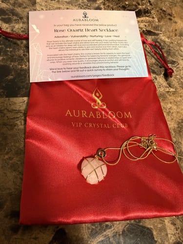 Customer's Rose Quartz necklace from the VIP Crystal Club shown with its red satin bag and info card.