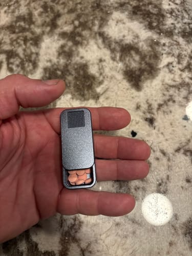 Customer holding the small metal Nano Case open in their hand, showing several pills inside.