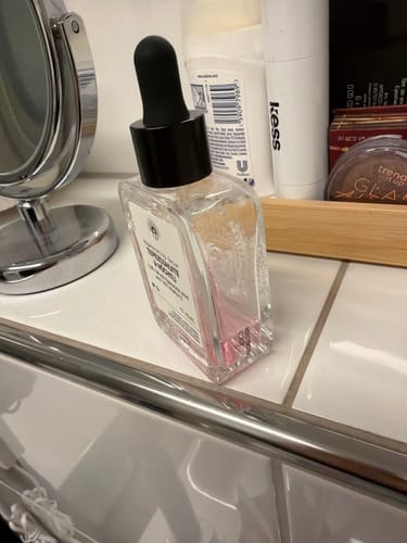 Customer's bottle of Regenerating Serum, partially used, on a bathroom counter.