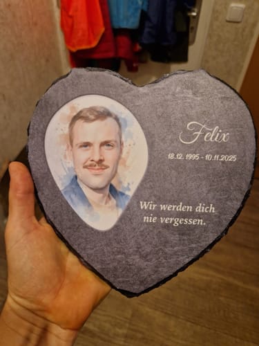 Ein Rezensent hält das personalisierte Schieferherz mit einem Foto und einer Gedenkinschrift in der Hand.