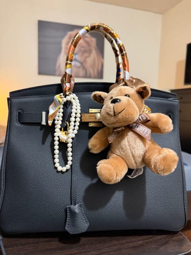 Customer's black LALUVA Warkin Leather Bag styled with a scarf, pearls, and a plush toy.