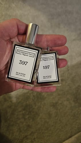 Customer's hand holding a clear bottle of 397 Inspired By Imagination perfume in front of a second bottle.