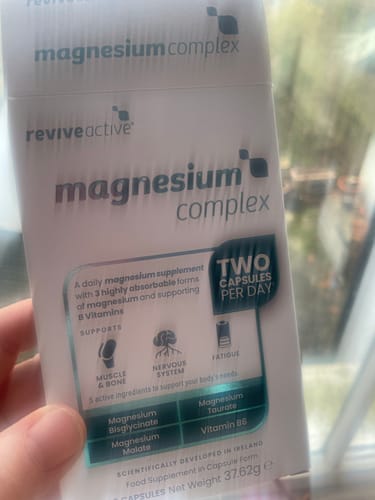 A reviewer holds the white and teal box of Revive Active Magnesium Complex supplements in their hand.
