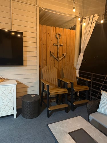Reviewer's two-tone Counter Height Bistro chairs set up separately on a decorated outdoor patio at night.